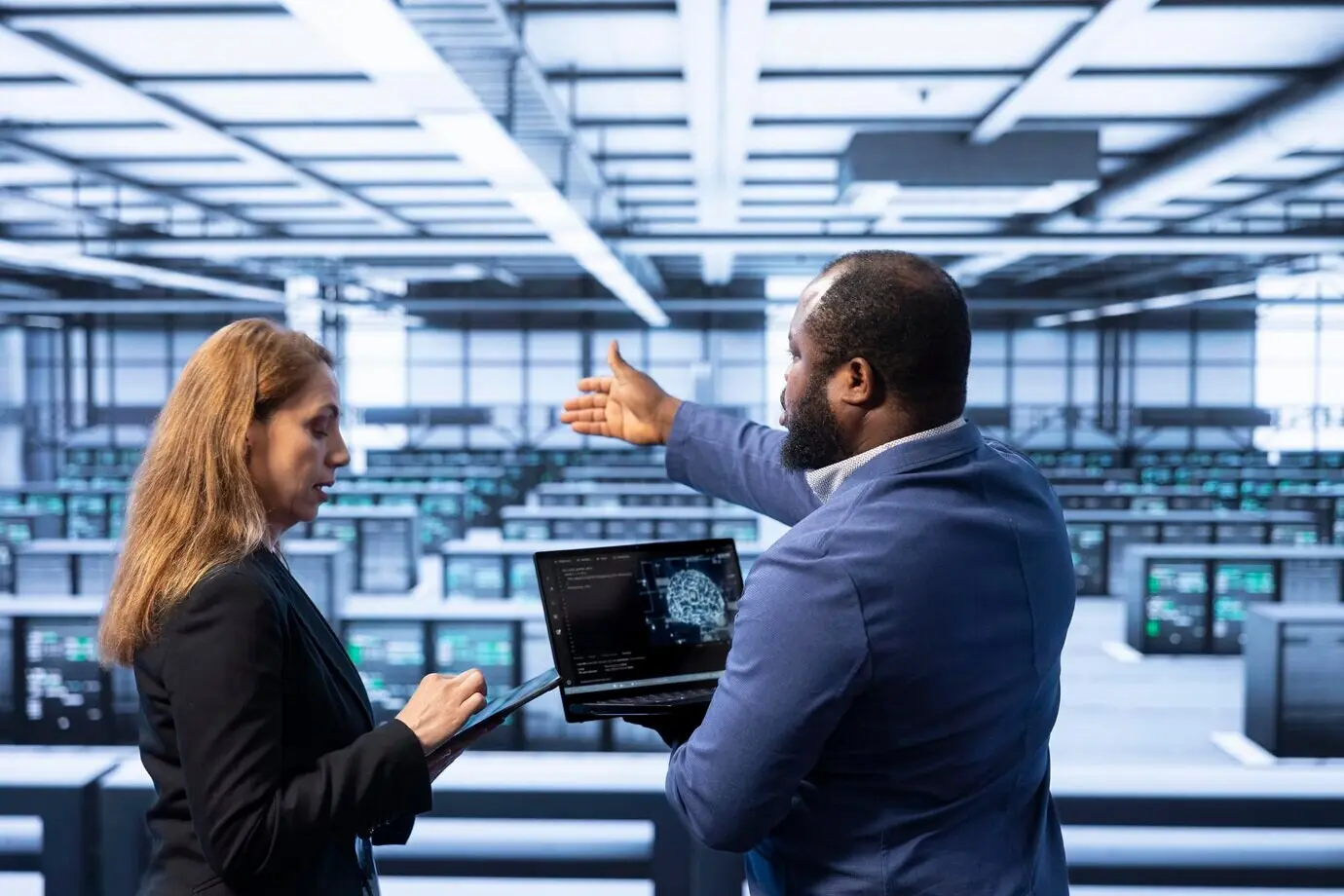 Команда техников в дата-центре с помощью ноутбука визуализирует ИИ.